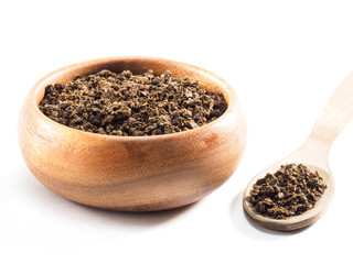 Fermented granular tea from Cherry (Cerasus) leaves in wooden cup with spoon on white background