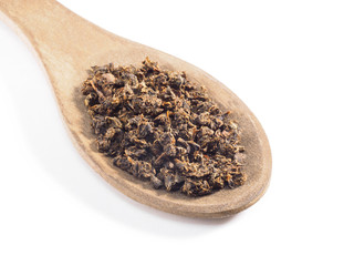 Fermented granular tea from Cherry (Cerasus) leaves in wooden spoon on white background