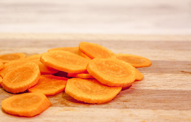A pile of chopped slices of carrots on a cutting board close-up.