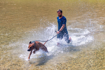 happy young man with his dog having fun swimming at river. Love animals love my pet