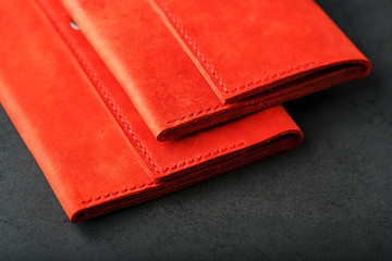 A pair of red genuine leather wallets with rivets on a dark background top view. Genuine leather