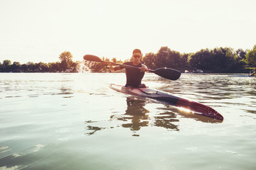Sportsman kayaking on a lake while the sun setting