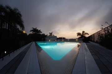 Beautiful outdoor nature landscape with sea ocean and coconut palm tree around swimming pool in hotel resort at sunrsie or sunset for leisure travel and vacation