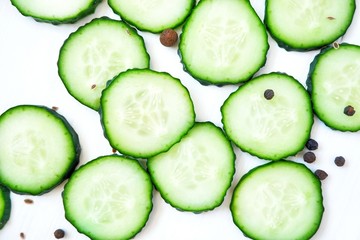 Slices of fresh cucumber and spices. Close-up on a white wooden background.