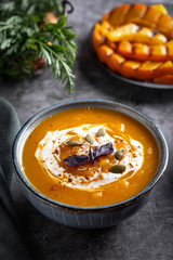 Pumpkin cream soup in the bowl, close-up.  Slices of grilled pumpkin. Gray background.
