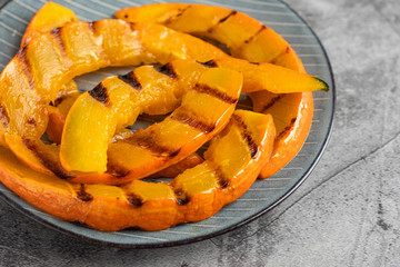 sliced pumpkin on a grill on a plate, close-up, copy space