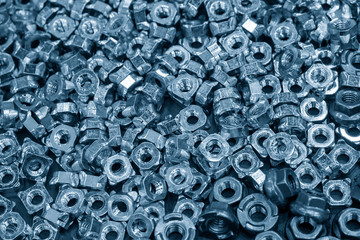 The pile of special purpose nuts in the light blue scene. The anti-slip nuts manufacturing process.