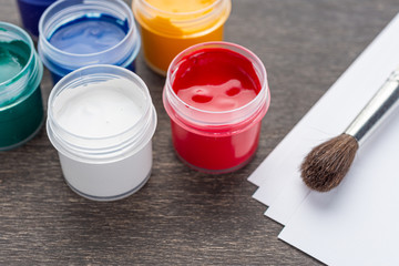 Looking down on three open paint cans of coloured paint stood on a shabby style wood floor