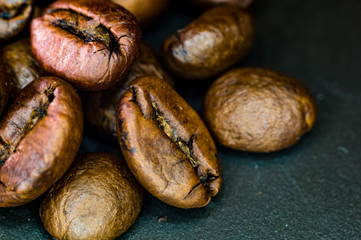 Brown roasted coffee beans on black background, close up, macro