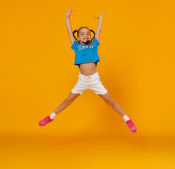 funny child girl jumping on colored yellow background.