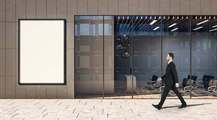 Blank white poster on a wall of business center and walking on a street businessman.