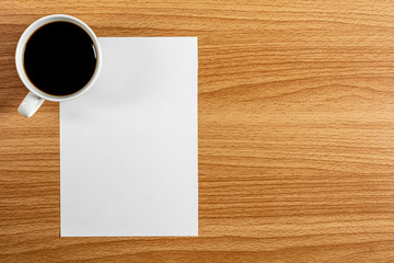 blank note paper and a coffee cup on wooden desk. - blank space for advertising text.