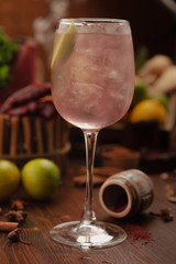cocktail dekorated lime in a vine glass on a wooden background. Background decorated with fruits and herbs.
