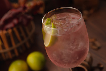 cocktail dekorated lime in a vine glass on a wooden background. Background decorated with fruits and herbs.
