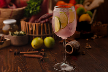 cocktail dekorated lime in a vine glass on a wooden background. Background decorated with fruits and herbs.