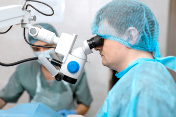 ophthalmologist surgeon looking through surgical microscope doing difficult operation