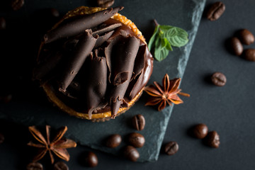 Chocolate cakes on black slatter board with mint, coffee beans on dark background, closeup photo....