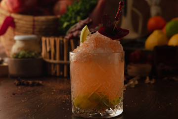 cocktail in rox decorated with a slice of lime on a wooden background. Background decorated with fruits and herbs.