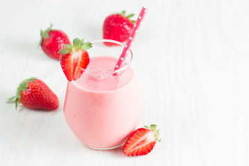 A glass of fresh strawberry smoothie on a wooden background. Summer drink shake, milkshake, juice and refreshment organic concept.