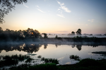 Obraz na płótnie Canvas Fog rises over the river during sunrise. Morning fog
