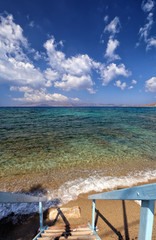 Fototapeta na wymiar Blue steps down to sandy beach and turquoise Aegean Sea, Agios Prokopios, Naxos, Greek Islands