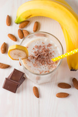 Fresh Made Chocolate Banana Smoothie on a wooden table. Selective focus. Milkshake with almonds. Protein diet. Healthy food and drink concept.