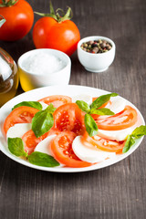 Close-up photo of caprese salad with ripe tomatoes, basil, buffalo mozzarella cheese. Italian and Mediterranean food concept. Fresh and healthy organic meal. Starter and antipasti.