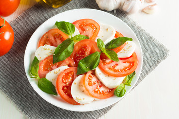Close-up photo of caprese salad with ripe tomatoes, basil, buffalo mozzarella cheese. Italian and Mediterranean food concept. Fresh and healthy organic meal. Starter and antipasti.
