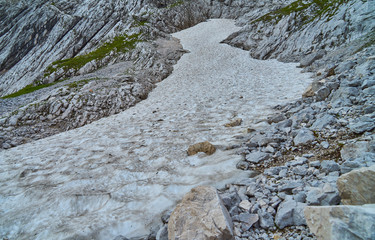 Last dirty remnant of a glacier tongue in a scree field in the Alps, thawed and melted by climate change