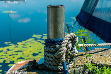 Fototapeta premium Bollard for mooring tied with a rope. Knecht on the pier for fastening ropes