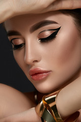 close-up portrait of elegant woman make-up with golden jewelry and black arrows