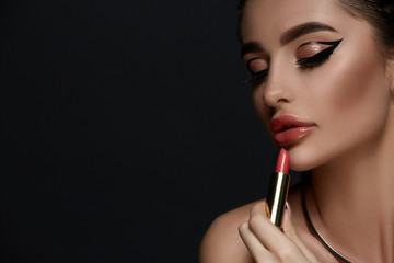 glamorous woman with evening make-up holding red lipstick and looking down