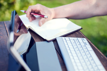 Businessman works with laptop and make records in notebook outdoor. Business and lifestyle concept