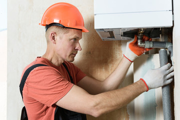 The worker is installing the gas boiler pipes.