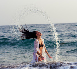 water splashing games made by a woman in the middle of the sea during sunset. summer time concept.