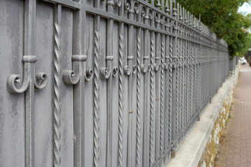 Fototapeta premium Beautiful decorative cast metal wrought fence with artistic forging.