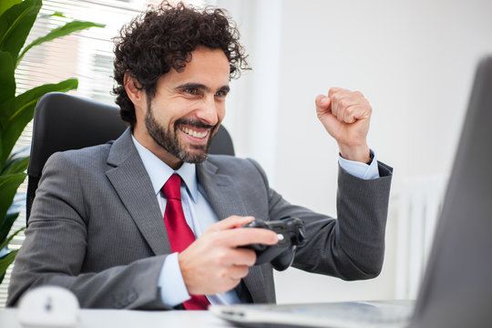 Businessman playing videogames in his office instead of working