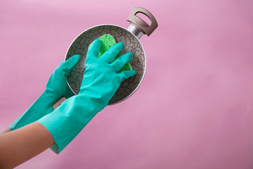 Hand in green protective glove washing a pan