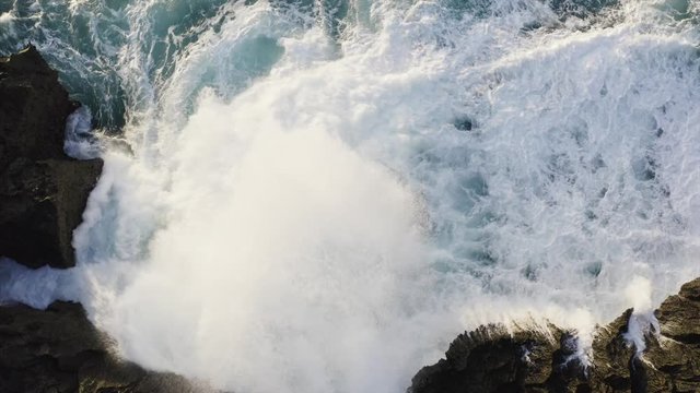 Power of nature. Top aerial view of stormy azure ocean and foamy waves crashing at rocky cliffs. Bali, Indonesia