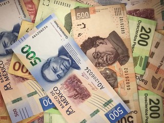 Mexican peso bills spread randomly over a flat surface