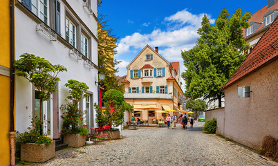 Cosy street in picturesque bavarian town Lindau at Lake Constance (Bodensee) in Germany. Traditional old german houses with cafe. Sunny summer day. - obrazy, fototapety, plakaty