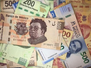 Mexican peso bills spread randomly over a flat surface
