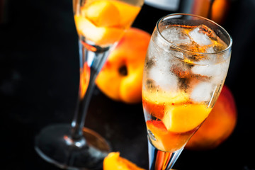 Bellini, alcoholic cocktail with sparkling wine, sugar syrup, lemon juice, peach and ice, gray table background, copy space
