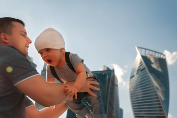 Father and one year old son against the sky and skyscrapers. Travel with children, the development of emotional intelligence. Early development.