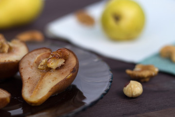 baked pears on dark glass plate with fresh fruits and nuts wooden background