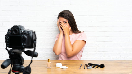 Young girl recording a video tutorial covering eyes and looking through fingers