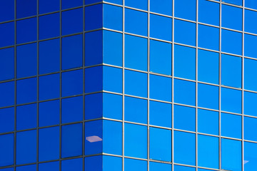 Fototapeta premium Glass blue square Windows of facade modern city business building skyscraper. Modern apartment buildings in new neighborhood. Windows of a building, texture.