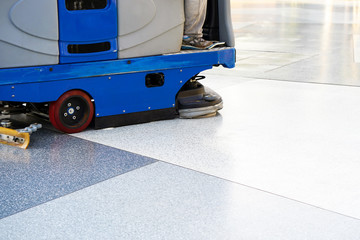 Man driving professional floor cleaning machine at airport or railway station or supermarket. Floor care and cleaning service
