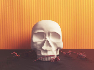 A decorative figure in the form of a human skull is on a yellow cardboard background. Nearby are the dried flowers.