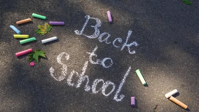 Written words Back to school on sidewalk zooming closer back and force. Real time 4k video footage.